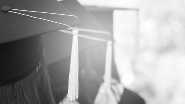 Black and white image, view from behind of students with cap and gown on