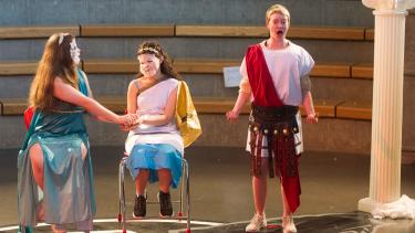 Three students dressed in costume performing