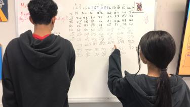 Two students looking at a whiteboard