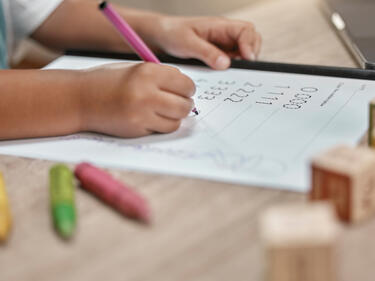 Education, paper and hands of child writing numbers