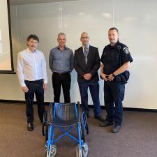 4 Adult males stand in front of wheelchair used by Eugene Reimer
