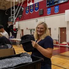 Volunteer in a gymnasium, packing backpacks for an event